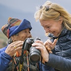 A female tourist has taken a photo of an elderly Bhutanese woman and is now showing the woman that photo on the screen on the back of the camera near Dranjo Goemba - buddhist monastery and school in the uper Paro Valley