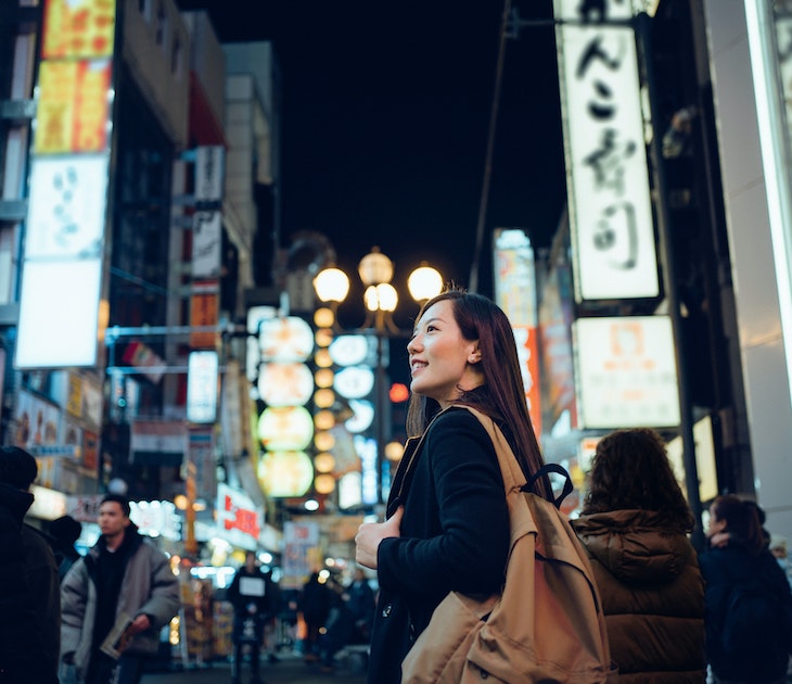 Smiling young Asian female traveller exploring and strolling along the busy and colourful neon signboard downtown city street at night in Osaka, Japan
1202888936