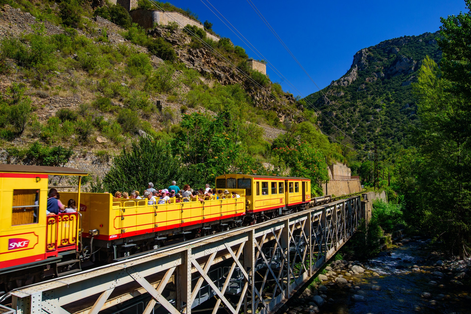 The Little Yellow Train (Le Petit Train Jaune) passing through Villefranche-de-Conflent, France