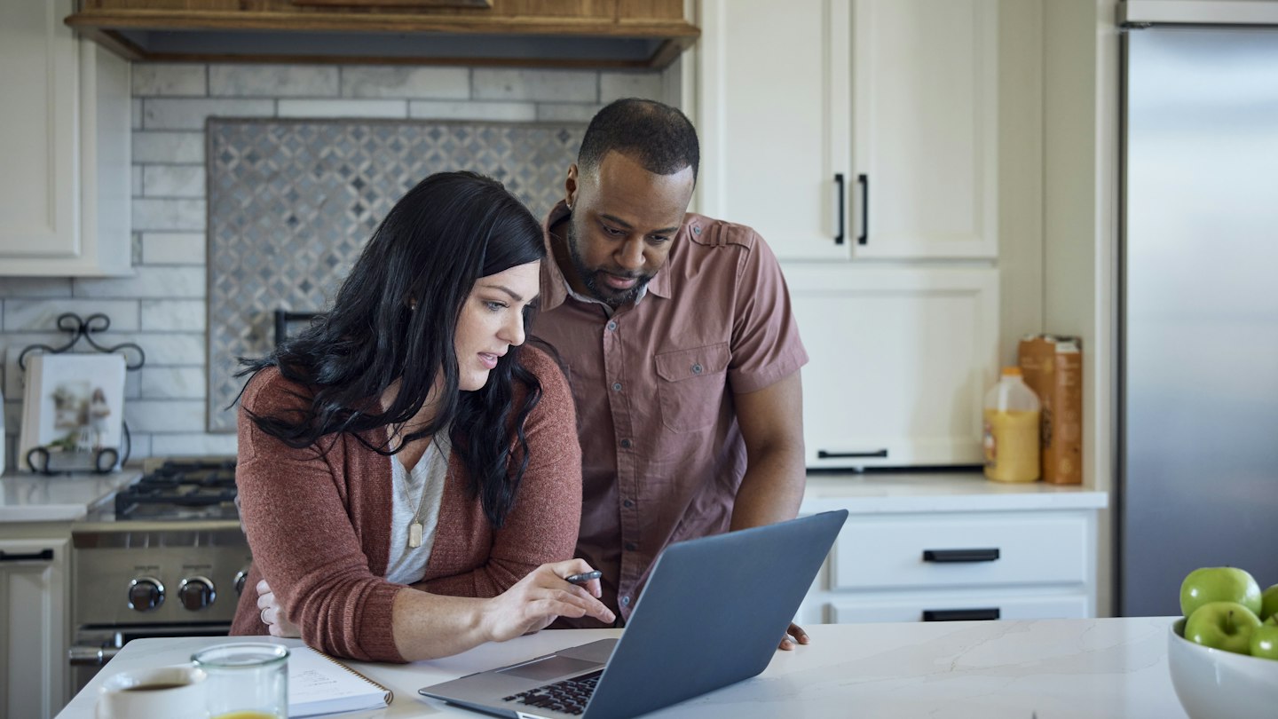 Caucasian woman and African American man sit at kitchen counter with breakfast working with pen, paper and laptop. - stock photo
Caucasian woman and African American man sit at kitchen counter with breakfast working with pen, paper and laptop.