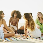 Smiling female friends relaxing on a blanket on a tropical beach at sunset while on vacation in Mexico