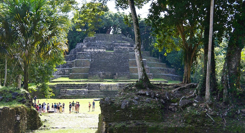 Wide shot of tourists dwarfed by the Temple of the Jaguar Mayan pyramid in Lamanai, Belize
1481511269