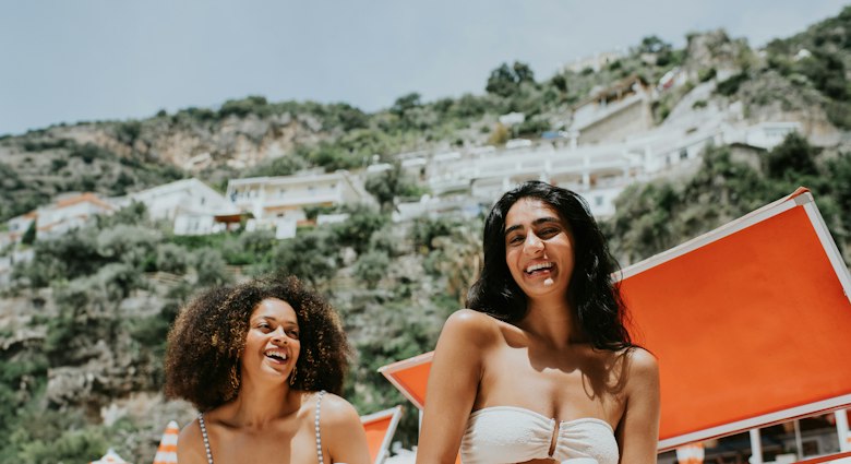 Two women laughing together on a beach on the Amalfi Coast