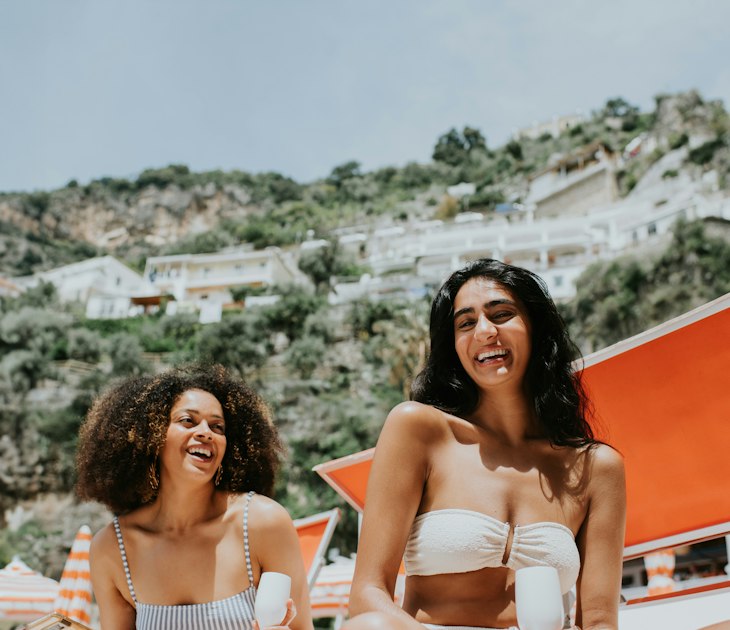 Two women laughing together on a beach on the Amalfi Coast