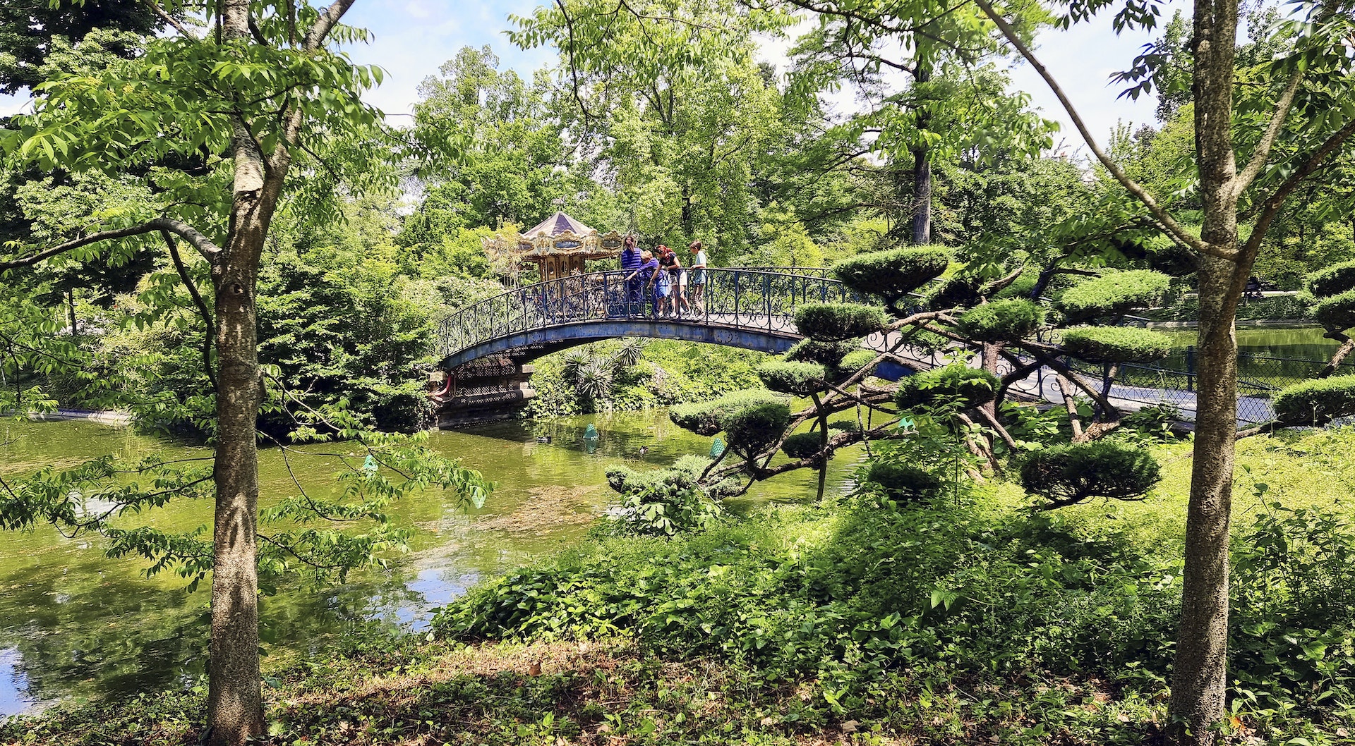 A family leaning over a bridge in the Jardin Public in Bordeaux