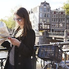 453872967
adventure, direction, travel, finding the way, city life
A woman holding a map next to her bike on a bridge in Amsterdam