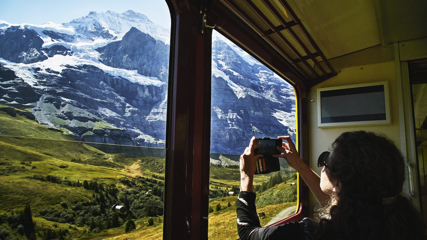 Woman taking photo with a smartphone of Jungfrau while riding in train