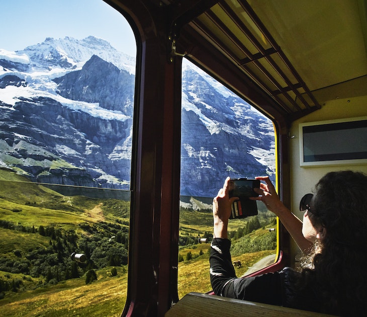 Woman taking photo with a smartphone of Jungfrau while riding in train