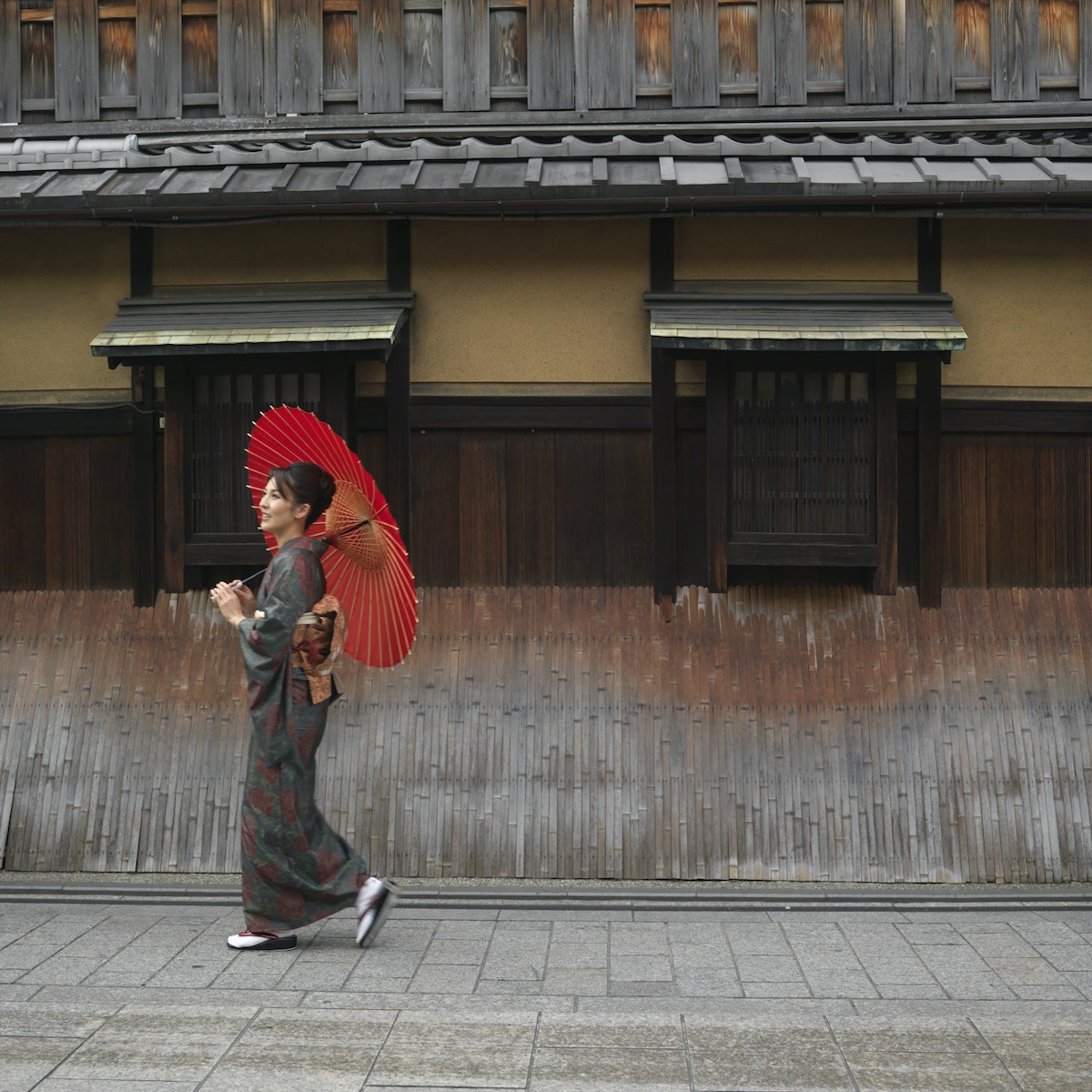 Japan, Kyoto, Gion, woman in kimono with red oilpaper umbrella, walking in street