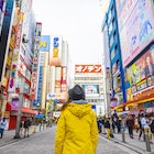 Woman with a yellow jacket walking in the electronic town district of Akihabara. 