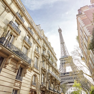 Low-angle view of the Eiffel Tower, as seen from a Paris street.