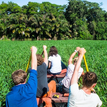 A group of wildlife surveyors canoes through a densely vegetation section of canal in Tortuguero National Park, Costa Rica.