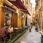 April 19, 2018: A couple eating pizza outside a pizzeria in the old city of Naples.