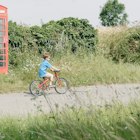 Boy Riding Bicycle In English Countryside
Boy cycling in English countryside past traditional British telephone box.