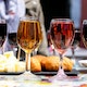 Defocussed brunette tasting different kind of wine standing on table with snacks outdoors