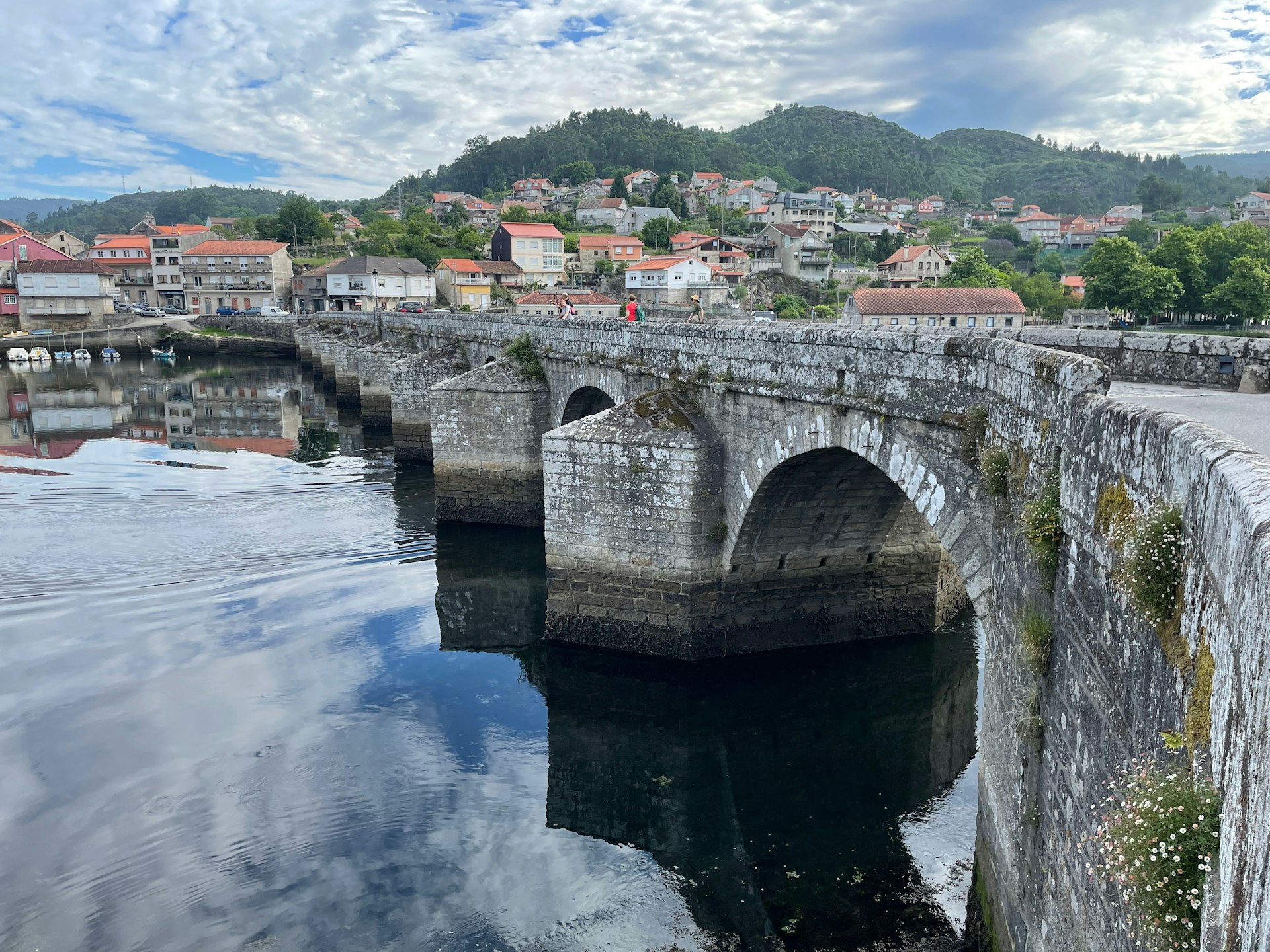 A Roman bridge spans a calm river in Arcade, Spain, along the Camino de Santiago